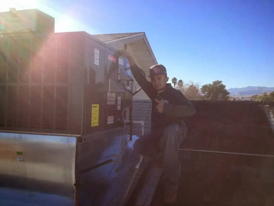 HVAC technician performing Air Duct Cleaning on a rooftop unit in LaGrange